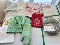 Overview of all kitchen linens including chef hat, mitt, potholder, towels, sealed tortilla warmer