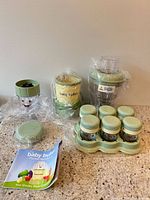 All main components: motor base, batch bowl, short cup with blade, six storage cups in tray, freezer tray, booklet