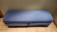 Top view of entire blue upholstered storage bench ottoman.