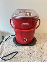 Front view of red Cuisinart ice cream maker assembled on countertop, power cord visible