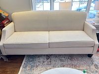 Front view of ivory three-seat sofa showing overall design and cushions