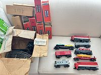 Overview of entire lot showing locomotives, freight cars, transformer, track, instruction sheet and original boxes on couch