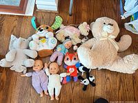 Group shot of all plush toys and baby dolls on floor