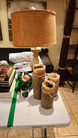 Lamp with shade, three pillar candles and jar candle on table