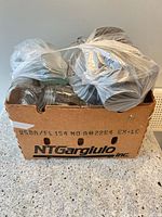 box containing clear glass mason jars and bagged lids