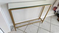 Front view of gold metal console table with mirrored top