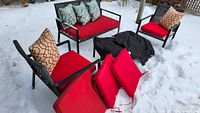 Full patio set in snow showing loveseat, chairs, table, cushions and pillows