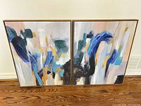 Both framed abstract canvases standing side by side on floor