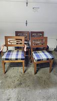 Set of four wood dining chairs with plaid cushions shown together