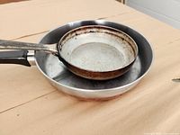 Two stacked frying pans, showing size difference and handles