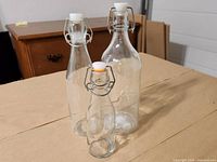 Three clear glass swing-top bottles varying in size