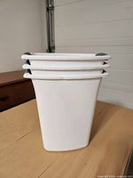 Side view of three stacked white wastebaskets