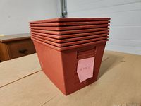 stacked view of eight red plastic totes showing open tops and tapered sides