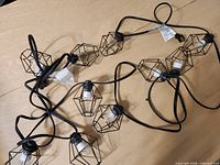 Full view of string light showing multiple caged bulbs on black cord