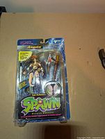 Front view of Angela action figure in original Spawn Deluxe Edition packaging showing figure and accessories