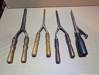 Five curling irons laid out showing overall condition and handles