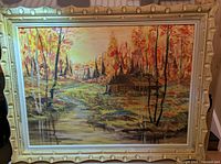 Full view of framed autumn cabin painting