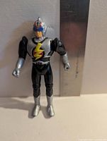 Front view of action figure with ruler showing height