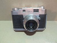 Front view showing Taron branding and fixed lens
