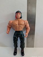 Front view of action figure beside ruler for scale