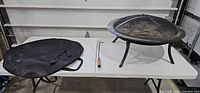 Fire pit with screen, poker, carry bag on table