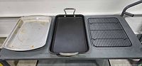 Overview of roasting pan, griddle pan, and cooling rack laid out side by side