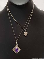 Two sterling silver pendant necklaces displayed on bust