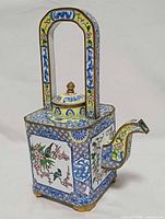 Front left view showing square body, arched handle, spout, floral panels