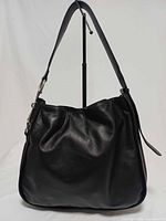 Front view of black leather hobo handbag on stand