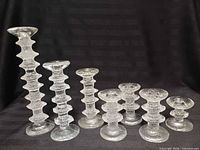 Seven Iittala Festivo candle holders assorted heights upright on black background