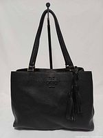 Front view of black Tory Burch McGraw leather tote showing logo and tassel