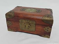 Front and top view of wooden jewelry box showing brass latch and corner fittings