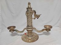 Front view of silverplated two-arm candelabra showing dragon, foo dog finial and ornate base