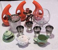 Group shot showing all items: orange vases, ice bucket, smoky glasses, green ceramics, white sugar bowl, brass piece, clear globe bowl