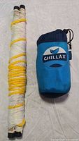 Blue Chillax hammock in stuff sack beside cord hammock wound on bars