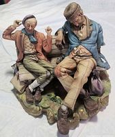 Front view of porcelain figurine showing two tramps on bench