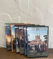 Front view of all six Downton Abbey season DVD cases standing in sequence