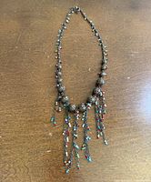 Full view of brass-tone necklace with filigree beads and tassels