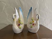 Front view of pair of ceramic swan planters showing floral decoration