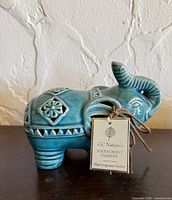 Left side of teal ceramic elephant with product tag visible