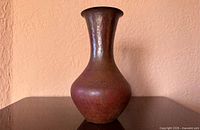 Full view of hammered copper vase on table