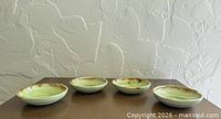 Four small green leaf stoneware dishes on table