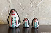 Front view of three graduated penguin figurines