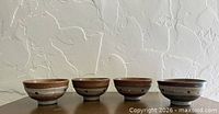 Four stoneware chawan bowls side by side showing exterior glaze and dot band