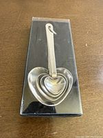 Front view of nested heart-shaped measuring spoons in clear-lid box