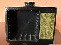 Front view of empty rotating cassette storage cube showing interior slots and faux wood panel