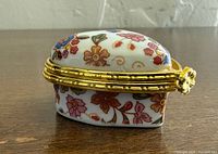 Side view of heart-shaped trinket box showing floral pattern and gold hinge
