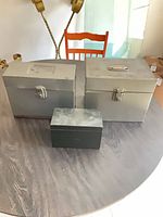 Three metal boxes on tabletop showing relative sizes and colors