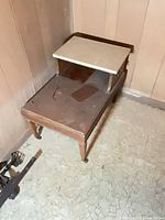 Full view of two-tier side table showing wood base, marble upper tier, and casters