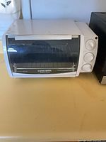 Front view of white Black & Decker compact toaster oven with three control dials